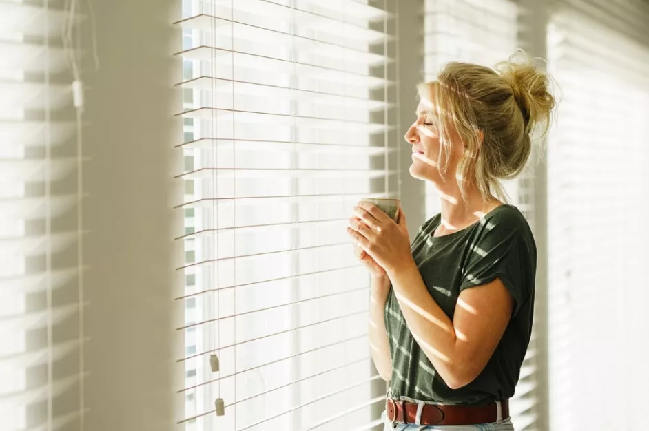 Vrouw geniet zonder zorgen van haar koffie en de zon op haar gezicht.