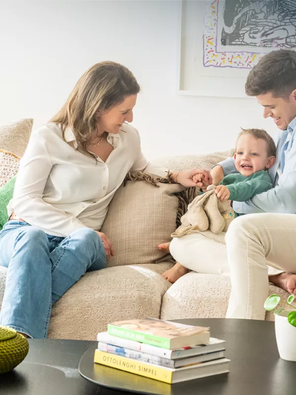 Anthony met vrouw en kind in woonkamer met beige en groene accenten.