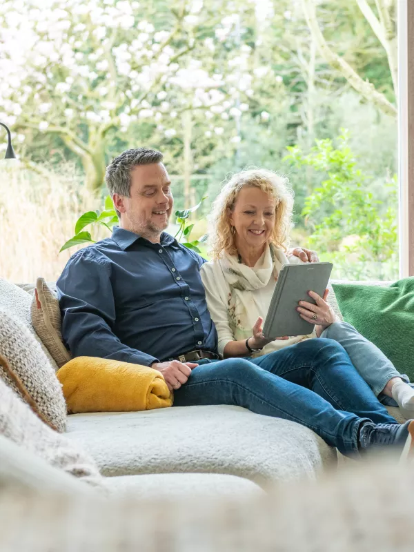 Man en vrouw bekijken hun energietarief vanuit de zetel.